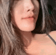 a close up of a woman 's face with long hair and a black tank top .