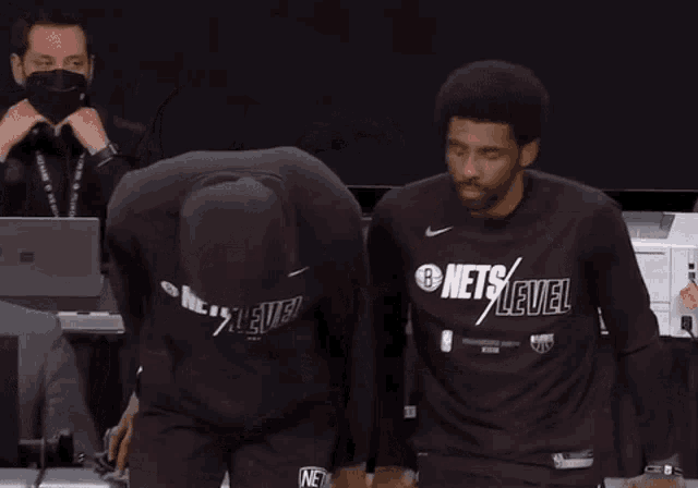 two basketball players wearing black nets level shirts are standing next to each other