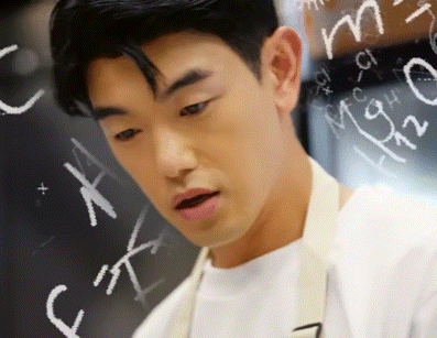a man in an apron stands in front of a chalkboard with the letters c and m on it