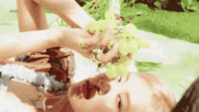 a woman is holding a bunch of grapes in her hands and drinking from it .