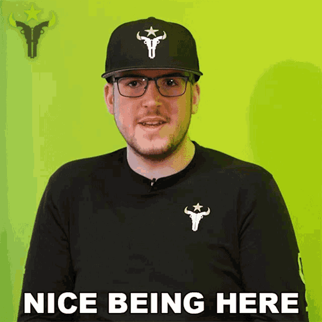 a man wearing glasses and a hat says nice being here on a green background