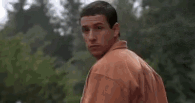 a man in a pink shirt is looking over his shoulder at the camera .