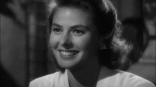a black and white photo of a smiling woman in a white shirt