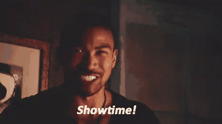 a man with a beard is standing in front of a picture frame and says showtime .