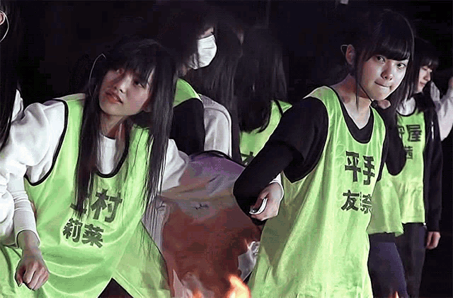 a group of young girls wearing green vests with chinese writing on them