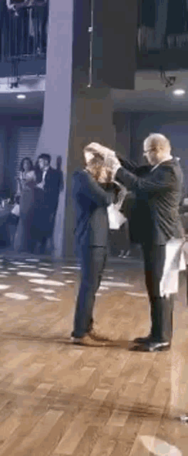 two men are dancing on a wooden floor in a room .