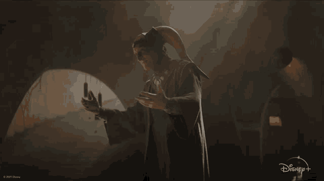 a man with horns is standing in a dark room with a disney logo in the background