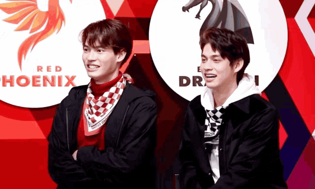 two young men are standing in front of a red hoenix sign