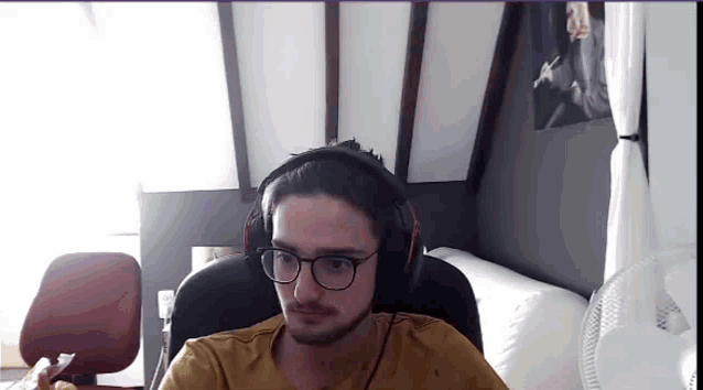 a man with glasses and headphones is sitting in a chair in a room .