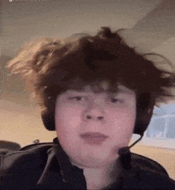 a boy wearing headphones and a microphone looks at the camera