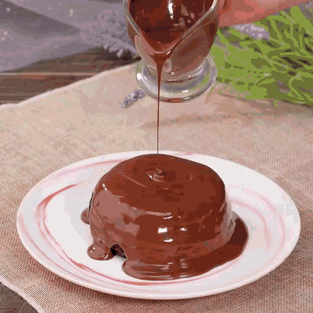 a person pouring chocolate sauce on a dessert on a plate