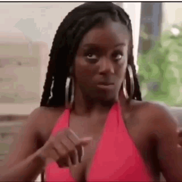 a woman in a red bikini is making a funny face and pointing at the camera .