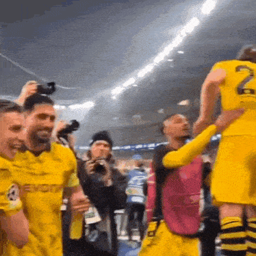 a group of soccer players in yellow jerseys are celebrating a victory .