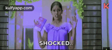 a woman in a purple dress is holding a book in her hands and says shocked .