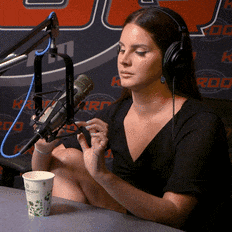 a woman wearing headphones talks into a microphone in front of a sign that says rod