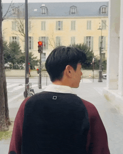a man is walking down a street with a red light behind him