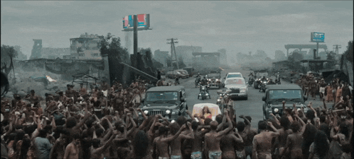 a crowd of people are gathered on a street in front of a billboard that says ' tnt '