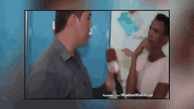 a man is talking to another man with a microphone and youtube.com is displayed