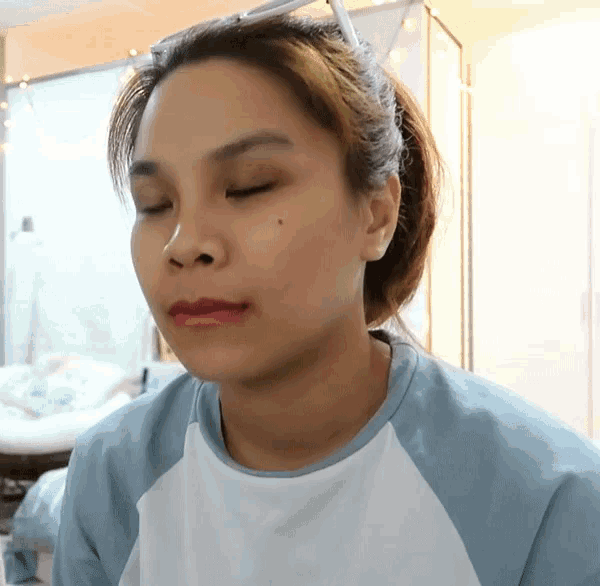 a woman with her eyes closed is wearing a blue shirt