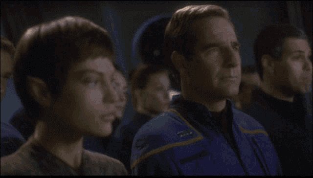 a man and a woman are looking at each other and the man has a badge on his uniform that says ' commander '