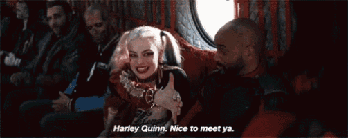 harley quinn is giving a thumbs up while sitting next to a group of men on a plane .