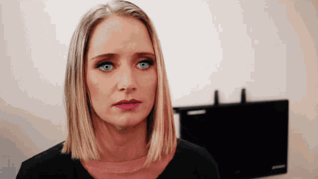 a woman with blonde hair and blue eyes is wearing a black shirt