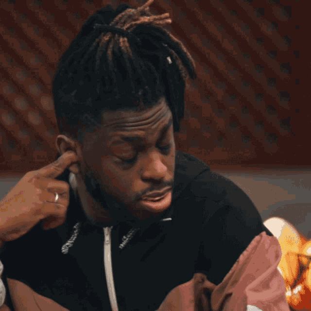 a man with dreadlocks and a jacket that says nike