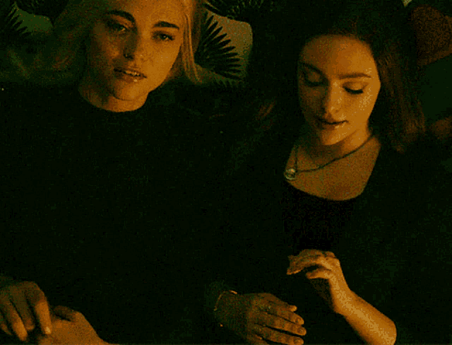 a couple of women are sitting next to each other in a dark room