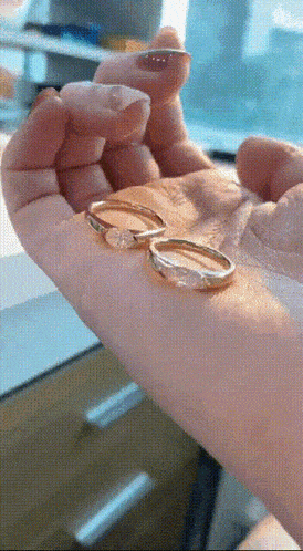 a close up of a person holding two rings in their hand