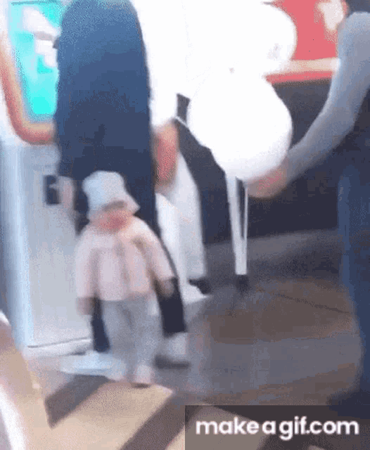 a baby is being held by a man while standing next to a woman in a pink jacket .