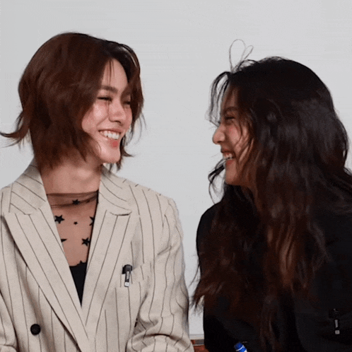 two women are looking at each other and one has a pencil in her pocket