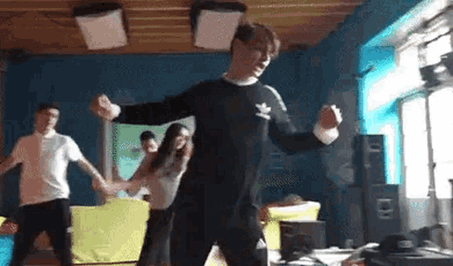 a group of young people are dancing in a room while holding hands .