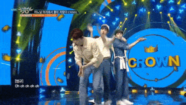 a group of people are dancing on a stage with a crown logo in the background