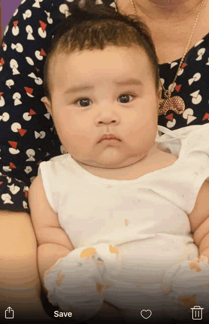 a baby is being held in a woman 's arms with a save button in the corner