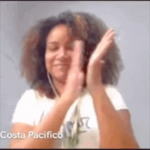 a woman with curly hair is wearing headphones and making a peace sign with her hands .