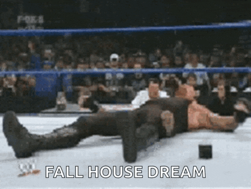 a man is laying on the ground in a wrestling ring with the words fall house dream written on the ground .