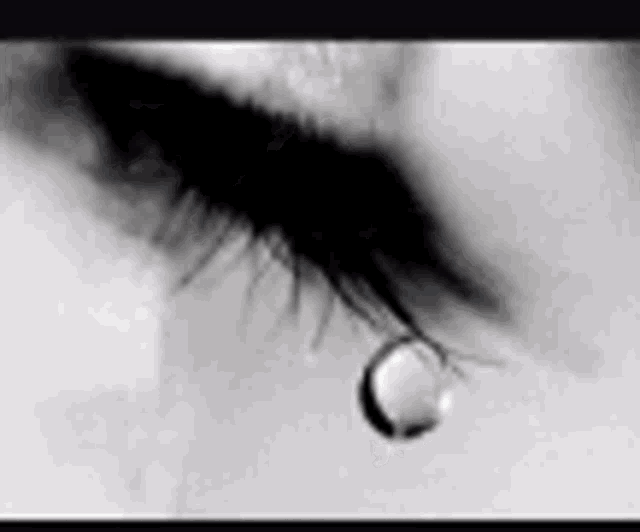 a close up of a woman 's eye with a tear coming out of it in a black and white photo .