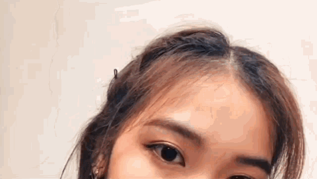 a close up of a woman 's face with her eyes closed and her hair in a bun .
