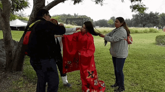 a woman in a red kimono is being helped by a man with a camera that says nikon