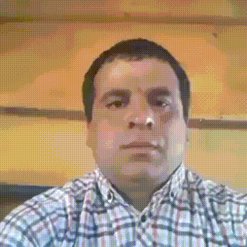 a man wearing a plaid shirt looks at the camera