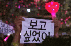 a person holding up a sign that says ' i love you ' in korean
