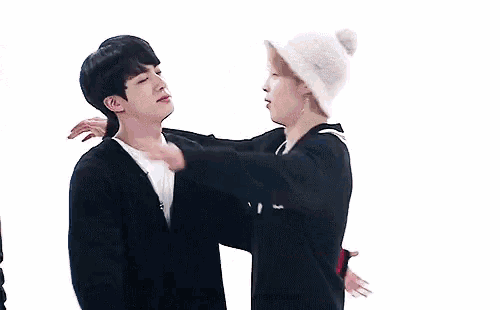 a group of young men are hugging each other and one of them is wearing a white hat
