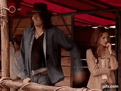 a man in a cowboy hat is standing next to a woman in a stable .