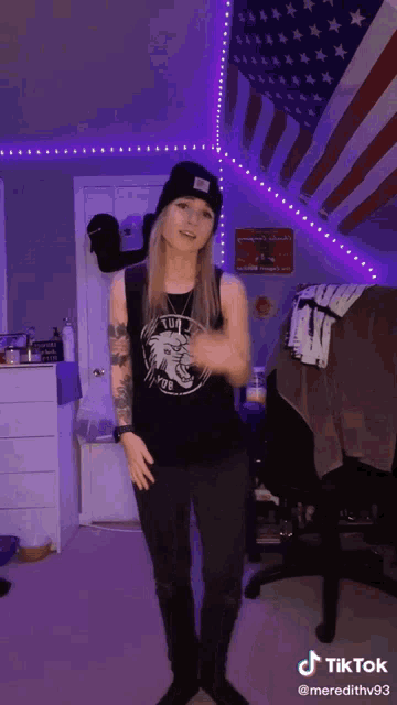 a woman is dancing in front of an american flag and a purple light behind her