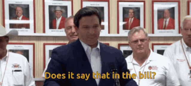a man in a suit says " does it say that in the bill " in front of a group of men