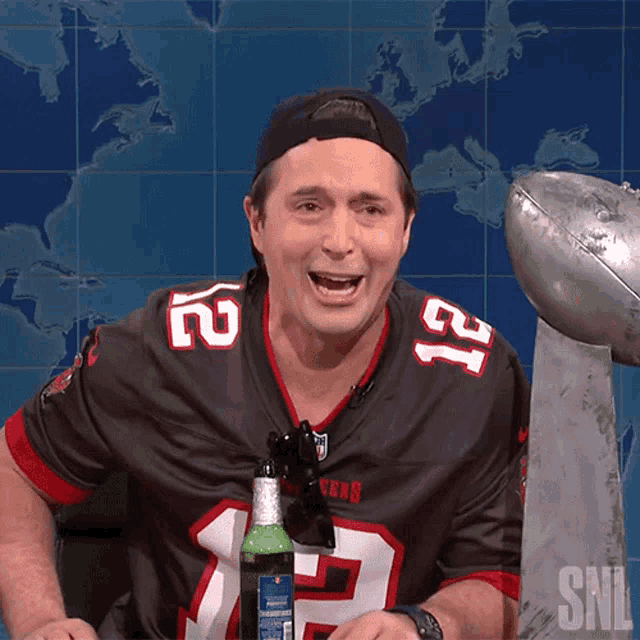 a man wearing a tampa bay buccaneers jersey holds a bottle of beer