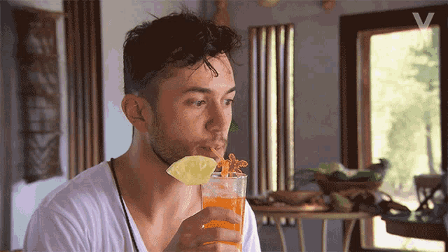 a man drinking from a glass with a pineapple slice on top