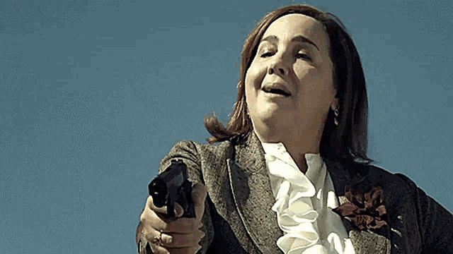 a woman is pointing a gun at the camera and smiling