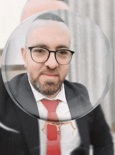 a man with glasses and a red tie is behind a glass