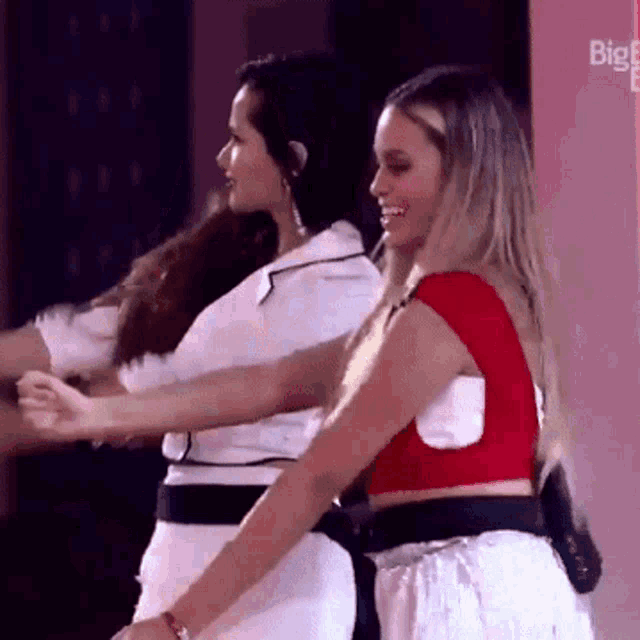 two women are dancing together and one is wearing a red crop top .